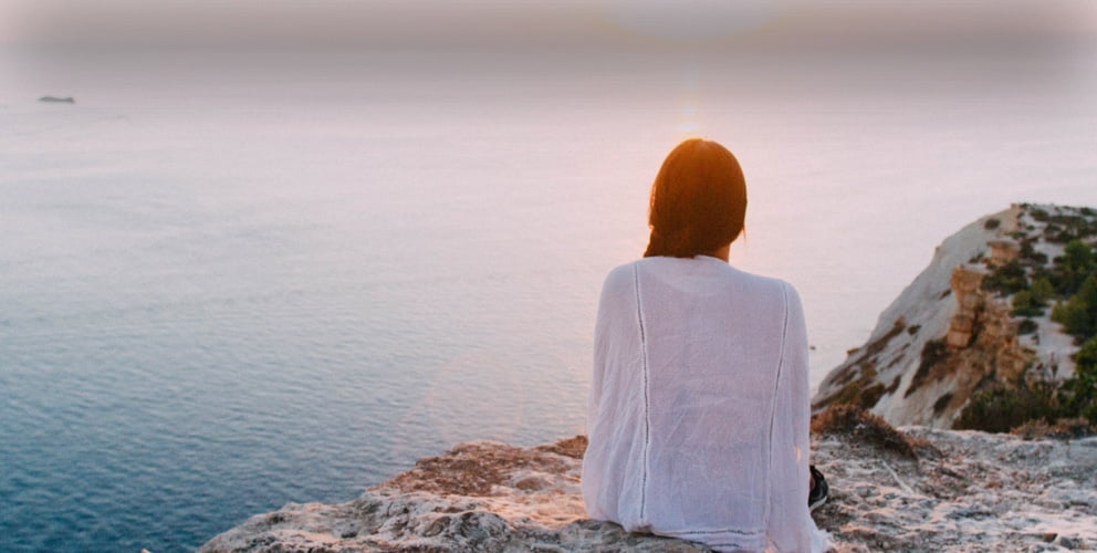 Hero image of woman sitting on cliff